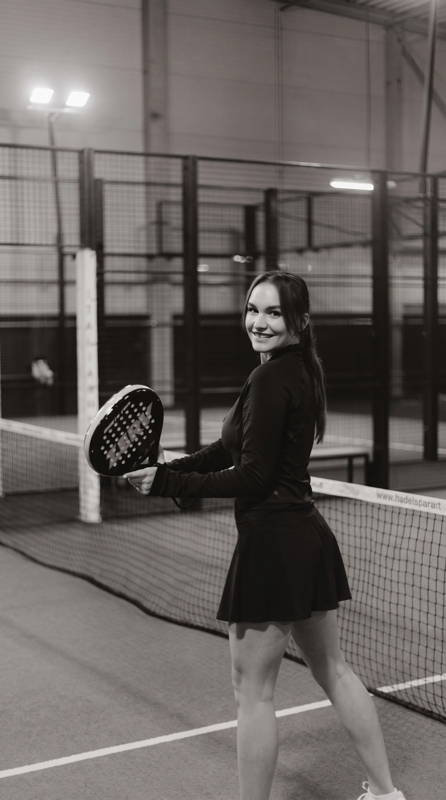 En padelspiller med ketsjer på en indendørs bane