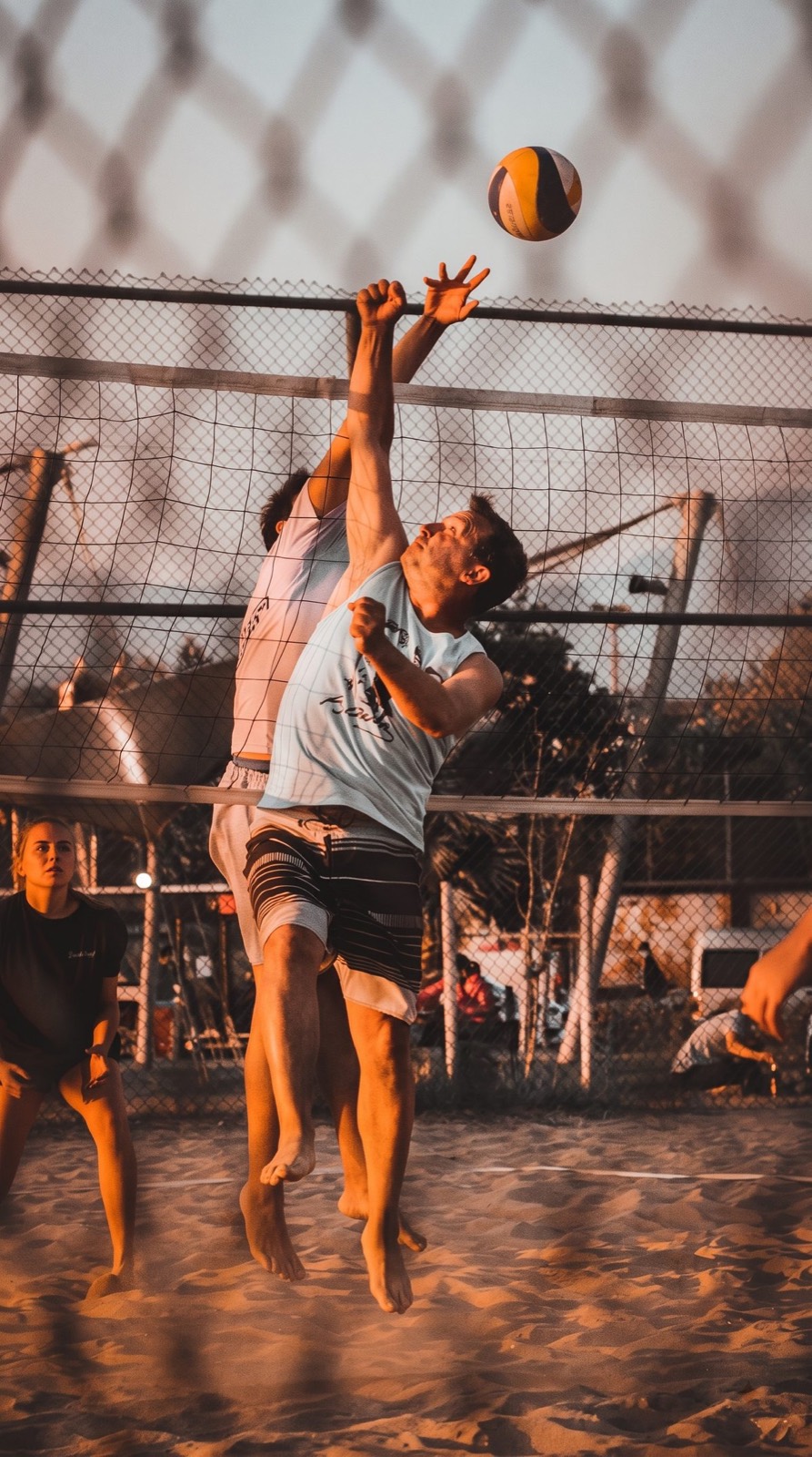 Players jumping for the ball at a beach volleyball net